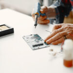 senior man with equipment soldering working home